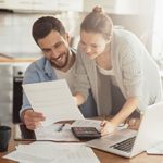 A couple examines their bills as they consider paying off debt versus putting their money into savings.