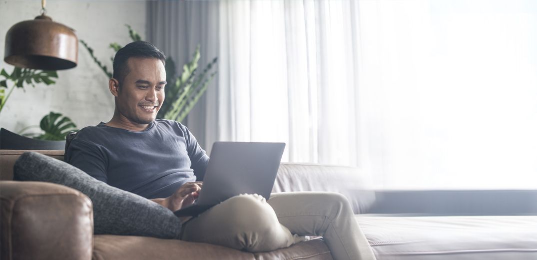 A man browses the Patelco website from his laptop at home.