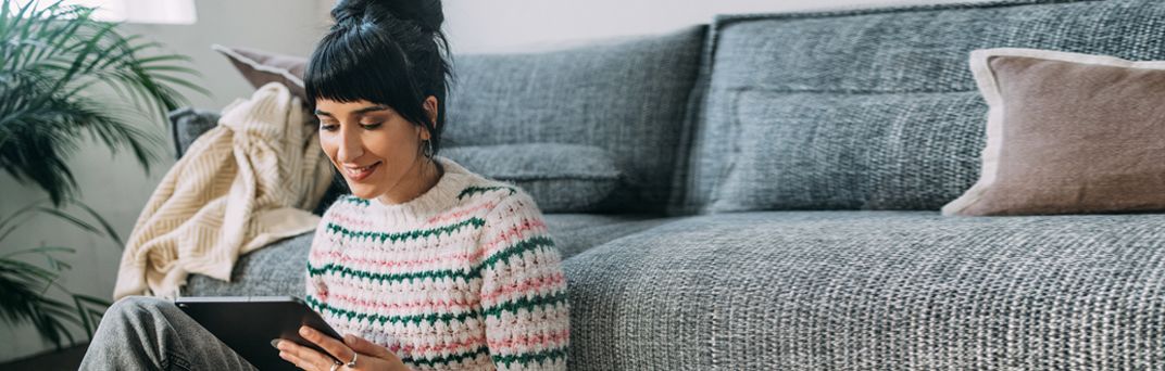 A Millennial uses her tablet to log in to Patelco Online from her living room.