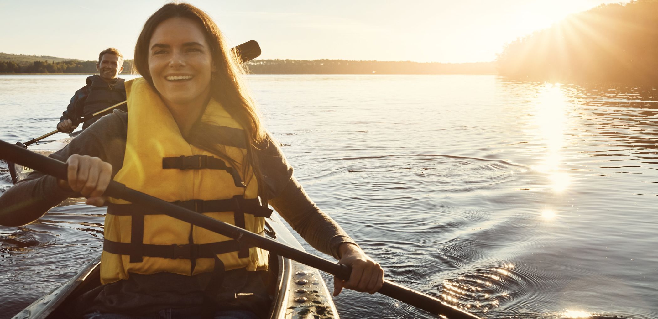 Smiling Patelco customers kayak on the Bay at sunset.