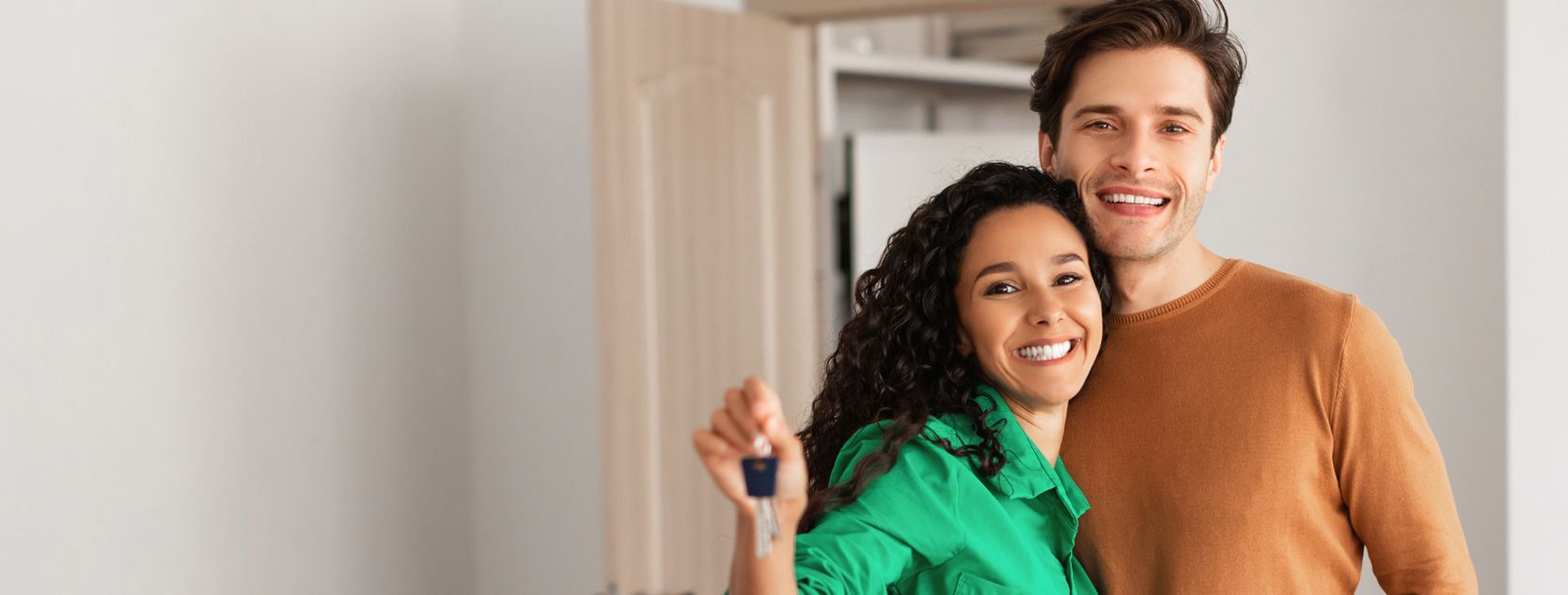 A man and woman hold the keys to a new home.