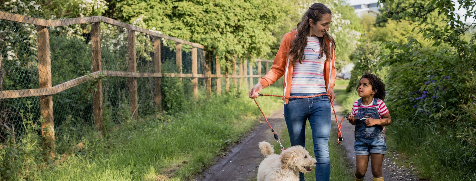 A Patelco member and her child walk a dog around their lush property.