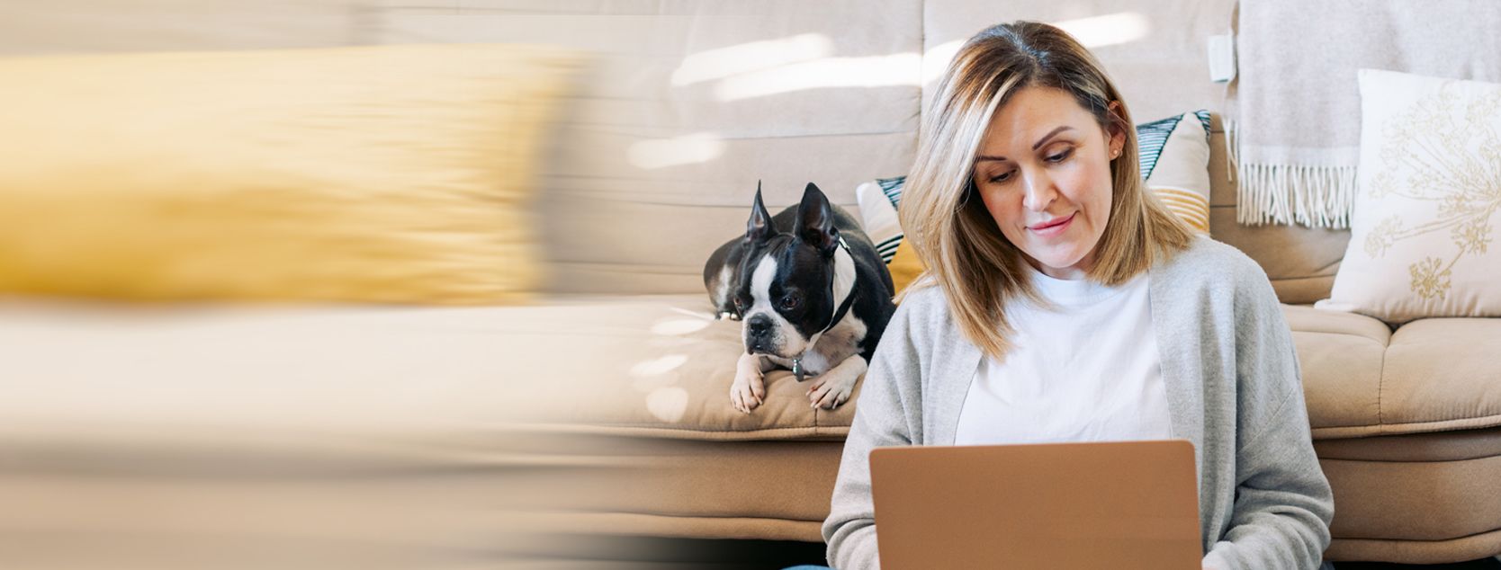 A woman manages her bank accounts from her laptop as her dog watches on