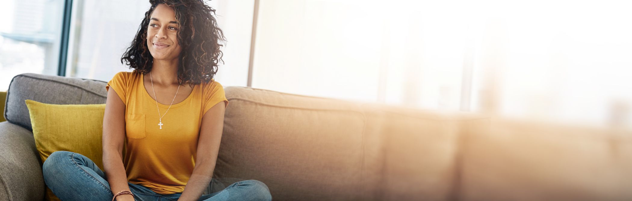 A woman smiles peacefully from her couch.