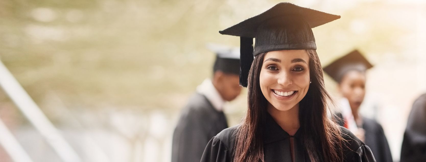 A smiling woman in her graduation cap and gown.