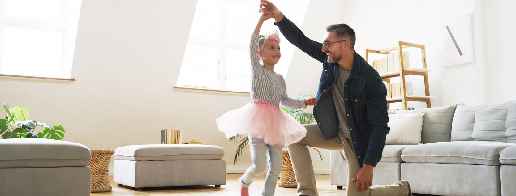 A father twirls his daughter, who is dressed up as a ballerina.