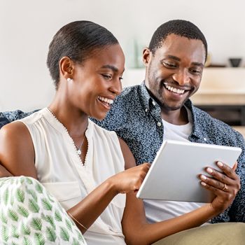 A cheerful couple uses their tablet to review their Health Savings Account on Patelco Online.