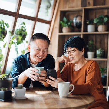couple drinking tea together and looking at information on wife’s phone
