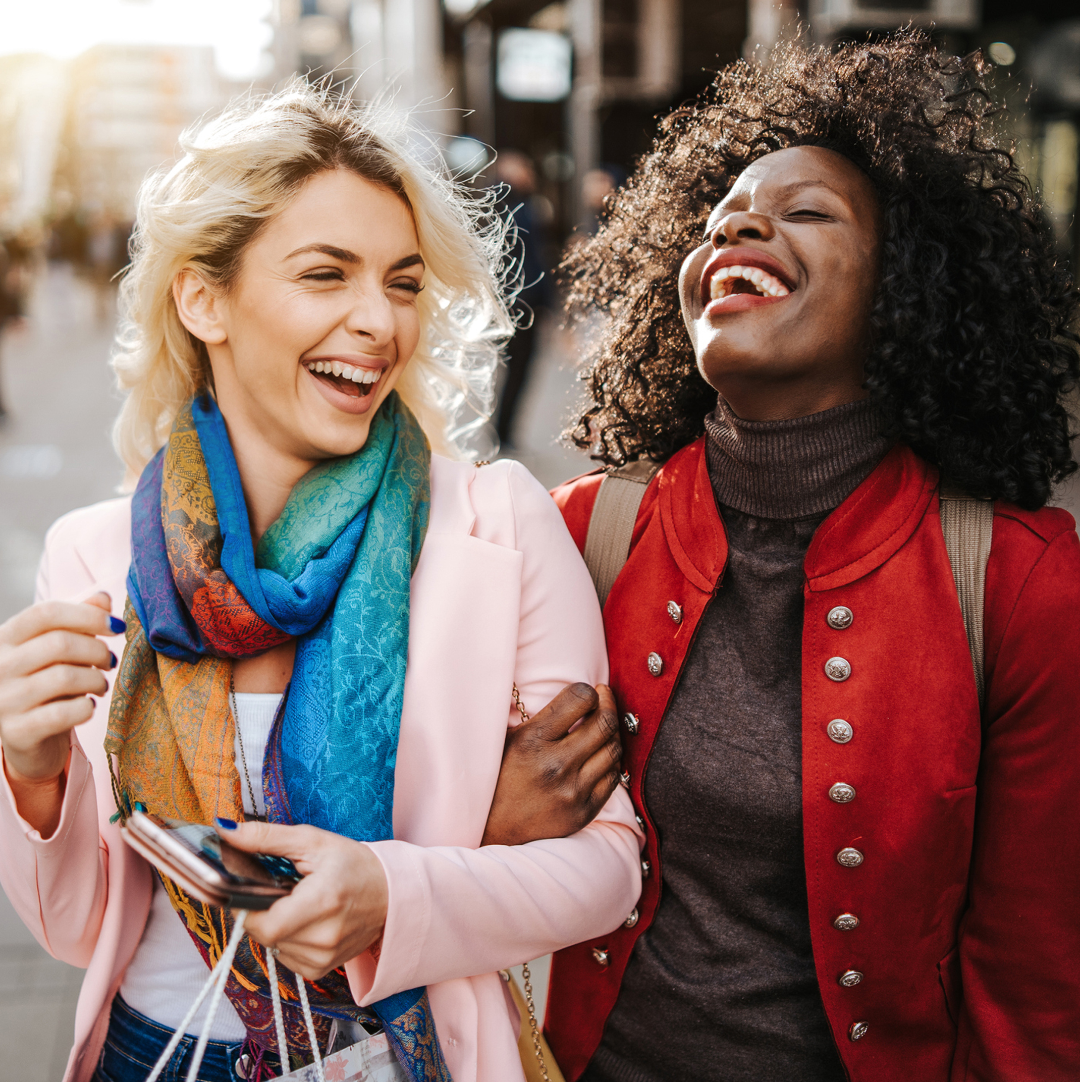Two friends in each other’s embrace laughing outside